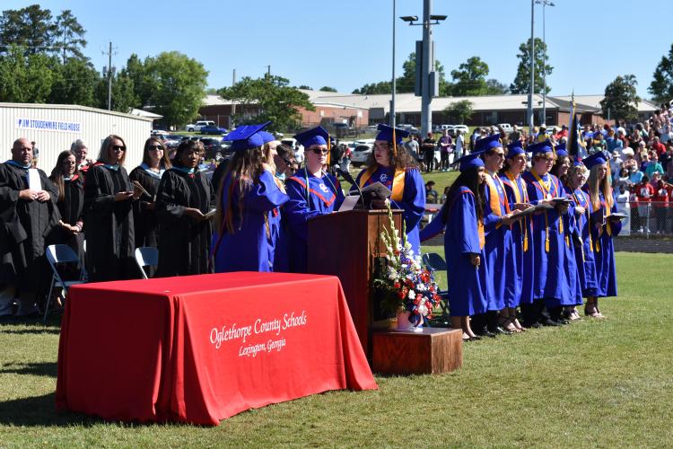 Graduates Meghan Hegwood, Valerie Romero, Willena Simmons and Hannah Wilson perform the OCHS alma Mater. Graduates tossed their hats after the song ended. (Photo/Sarah Evans)