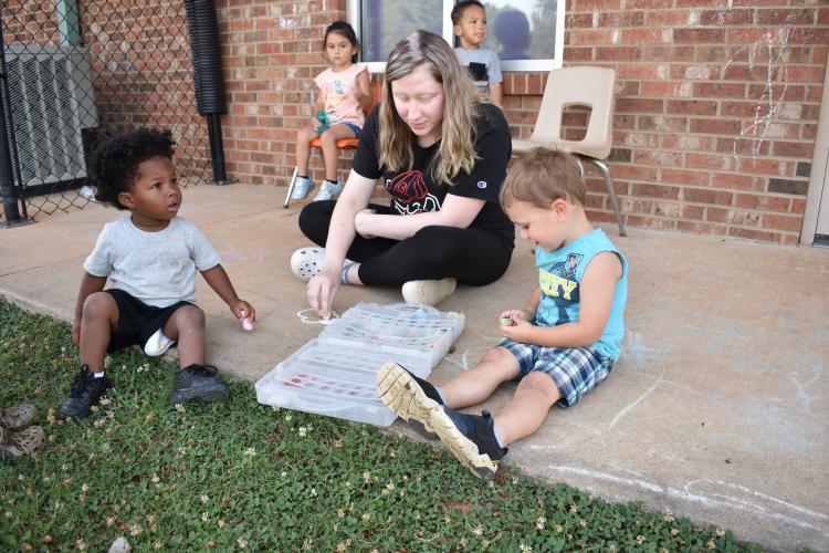 Amanda Brewer creates chalk art with children attending the 2-year-old class. Instructors often work on art projects with a small group of children while the rest enjoy supervised play. (Photo/Sarah Evans)