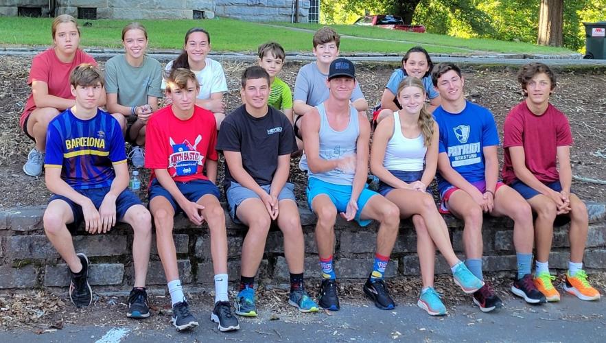 Members of the cross country teams sit for an impromptu team photo in front of the courthouse. (Submitted Photo)